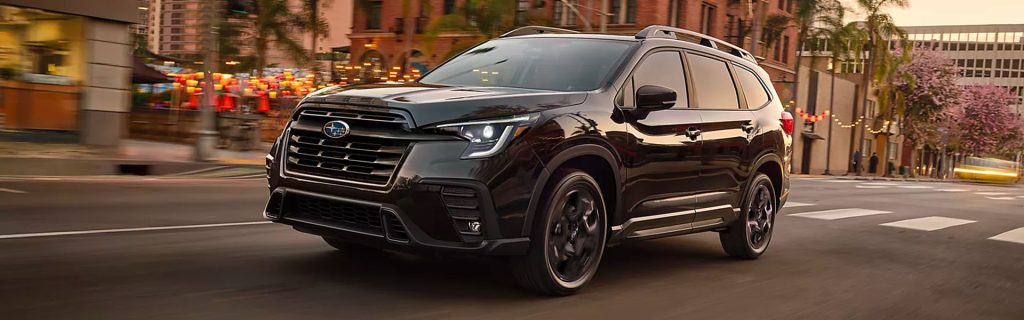 A black Subaru Ascent SUV driving through a city street.