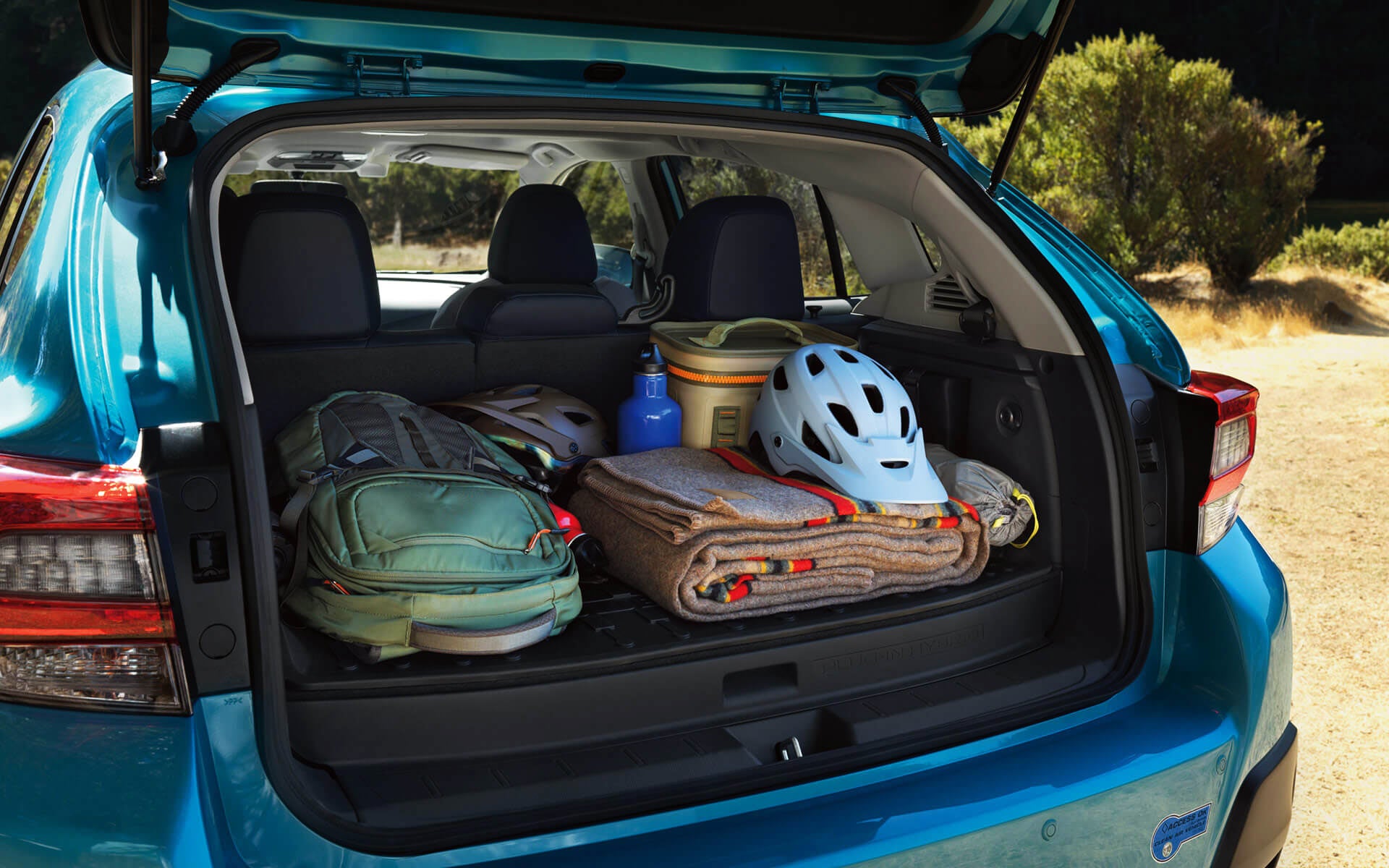 A backpack, blanket, and bike helmet in the rear cargo area of a Crosstrek Hybrid | DELLA Subaru of Plattsburgh in Plattsburgh NY